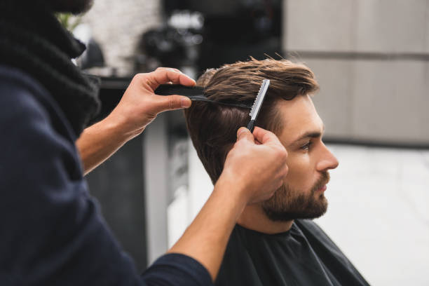Male client getting haircut by hairdresser Skillful stylist is making hairdo by special scissors. Young man is sitting with relaxation razor blade photos stock pictures, royalty-free photos & images