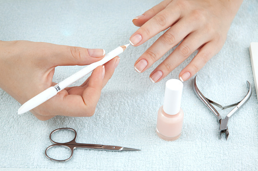 Woman making  manicure using nailfile with nail care tools background