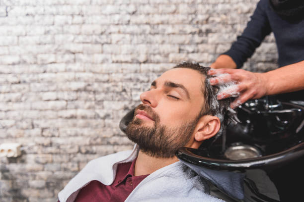 młody mężczyzna cieszący się hairwash w salonie kosmetycznym - men hairdresser human hair hairstyle zdjęcia i obrazy z banku zdjęć