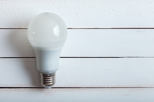 led bulb, an economical lamp lies on a wooden background from boards.