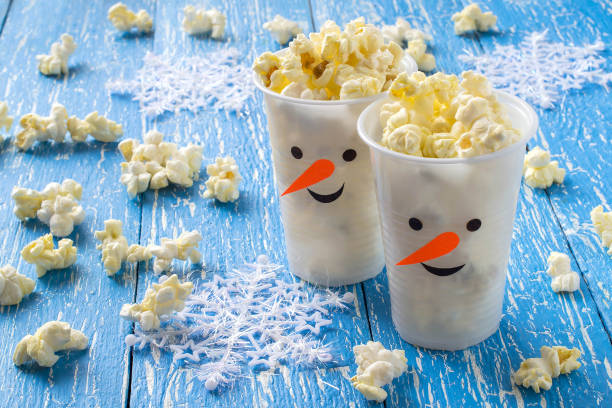 Plastic cups in the form of snowmen with popcorn stock photo