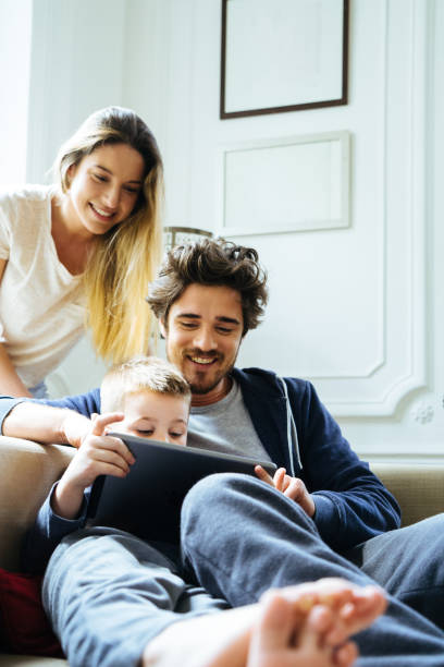 Cheerful Young Family Looking At Digital Tablet Together stock photo