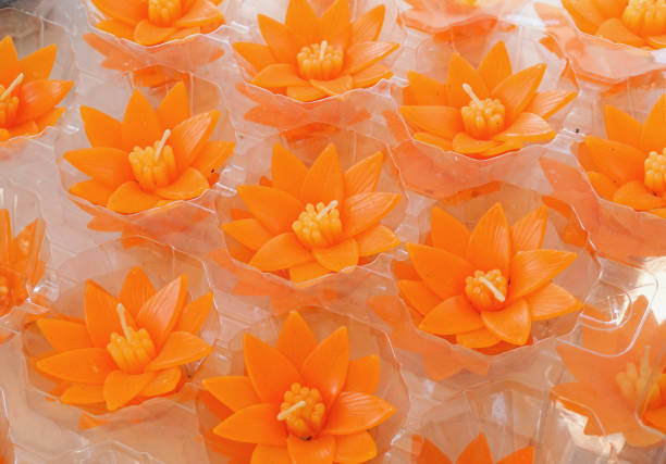 Small carved orange lotus flower shape candles for make merit in Buddhist Thai temple