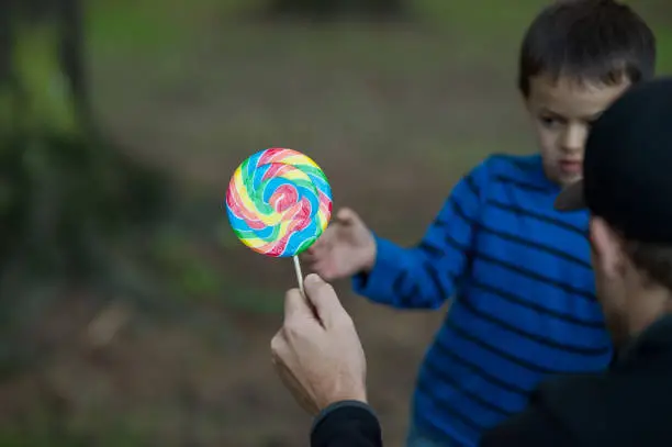 Six or seven year old boy accepting lollipop from strange man.