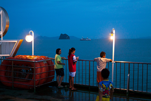 Surat Thani, Thailand - May 11, 2014: Capture of thai people on ferry pier in Surat Thani before sunrise. People are waiting for ferry to Koh Samui.