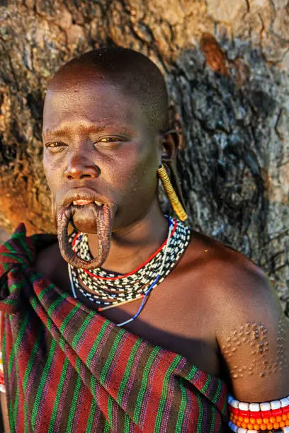 Mursi tribe are probably the last groups in Africa amongst whom it is still the norm for women to wear large pottery or wooden discs or ‘plates’ in their lower lips.http://bhphoto.pl/IS/ethiopia_380.jpg