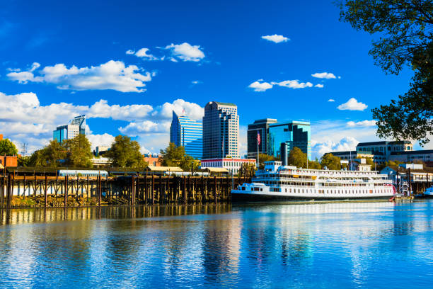 Downtown Sacramento Skyline with Historic Riverboat Downtown Sacramento skyline with the Sacramento River and the historic Delta King riverboat in the foreground and puffy white clouds and a deep blue sky in the background. sacramento stock pictures, royalty-free photos & images