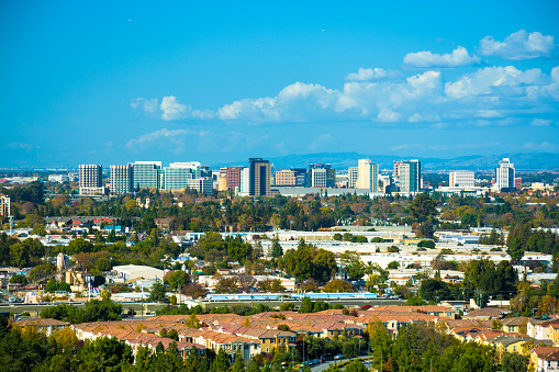 Vista of the San Jose skyline, with puffy clouds in the background and residential areas in the foreground.