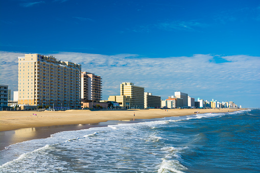 Virginia Beach’s coastal skyline with hotels and condominium towers, and with the Virginia Beach coastline and people in the foreground.  Virginia Beach is part of the Hampton Roads area.