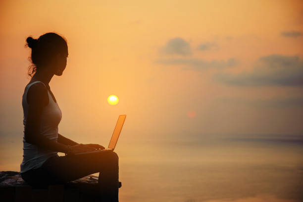 Lady freelancer with laptop on sunset stock photo