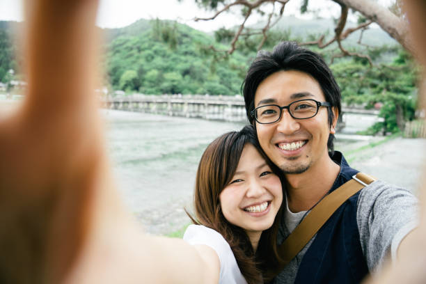 公園で屋外で自分撮りをする陽気な日本のカップル - 自分撮り ストックフォトと画像