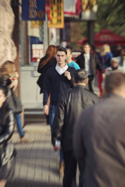 in motion, blurred,  young man walking in a rainy day, passing through parked cars