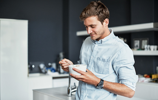 Shot of a happy young man enjoying breakfast in his kitchen at home