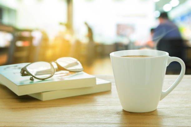 istock Cup of coffee, eyeglass and book on wooden table. 640321164