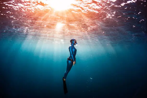 Woman free diver ascending from the depth in a tropical clear sea
