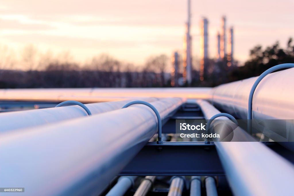 tubos longos de aço em fábrica de petróleo bruto durante o pôr do sol - Foto de stock de Oleoduto royalty-free