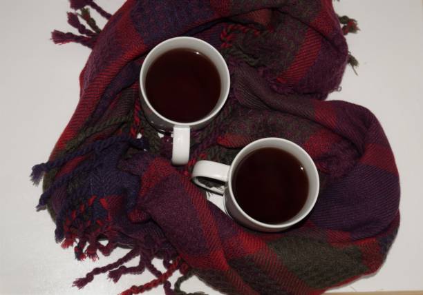 istock Two cups of tea in red heart shaped scarf 640325816