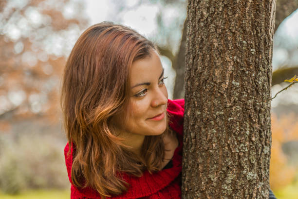 istock Close up beautiful young woman hiding behind a tree. 640333370