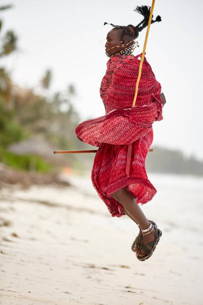 eleganter maasai-mann springt am strand von sansibar. - masai africa dancing african culture stock-fotos und bilder