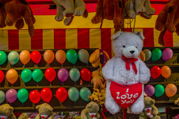 White big teddy bear with a big red heart with the words I love you, colorful balloons, plush toys