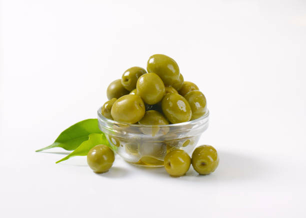 bowl of green olives bowl of green olives on white background green olive fruit stock pictures, royalty-free photos & images