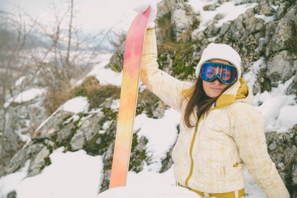 istock Woman holding snowboard with mountains in background 640341172