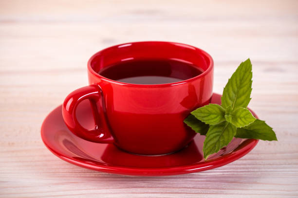 Red cup of tea with green leaves stock photo