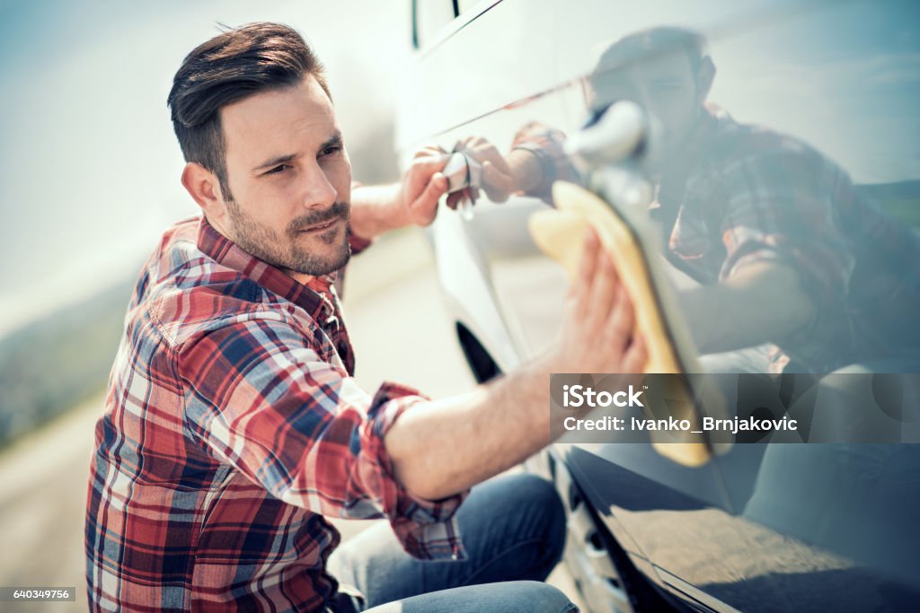 Giovane uomo pulisce la sua auto all’aperto - Foto stock royalty-free di Automobile