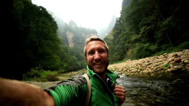 Young man hiking takes smart phone selfie, China