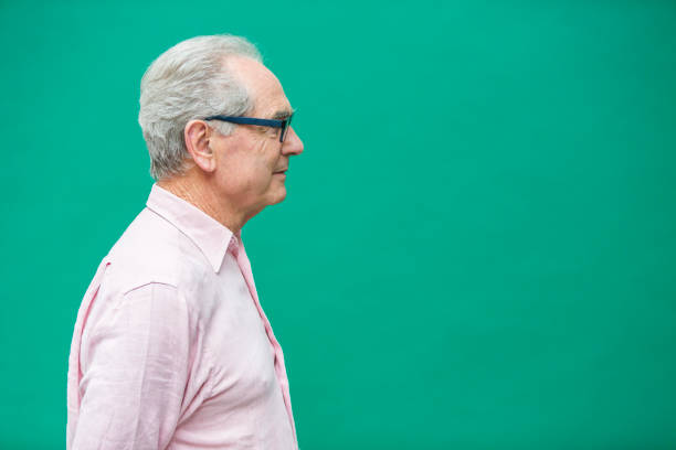 Senior man pulling a face in front of a green background wall