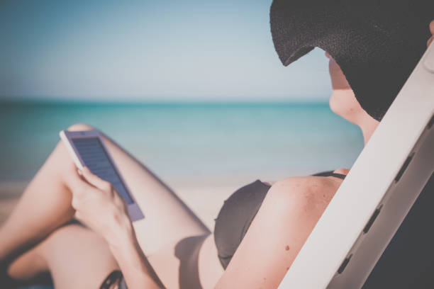 istock Woman Relaxing at Beach on Chair with Electronic Book Reader 640807028