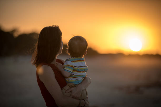 istock Single Mother Holding Baby Boy at Beach Sunset 640807056