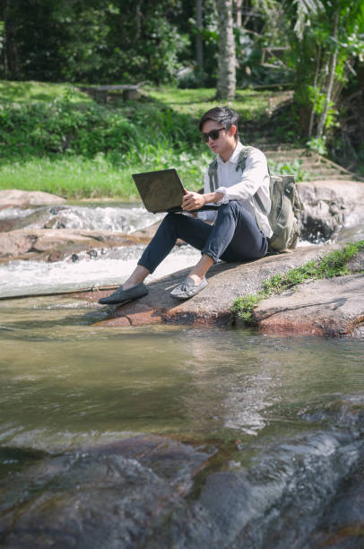 istock Businessman with backpack and laptop and phone at  waterfall  the forest. 640829088