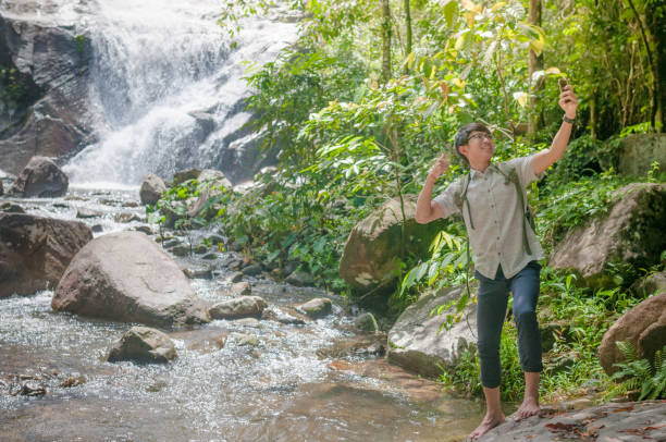 istock Businessman with backpack and laptop and phone at  waterfall  the forest. 640832236