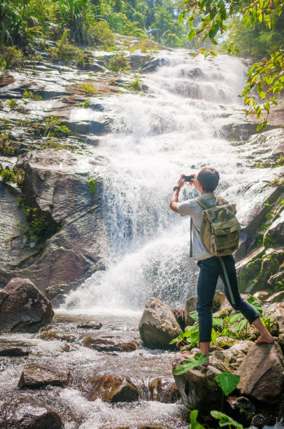 istock Businessman with backpack and laptop and phone at  waterfall  the forest. 640832256
