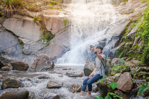 istock Businessman with backpack and laptop and phone at  waterfall  the forest. 640832284