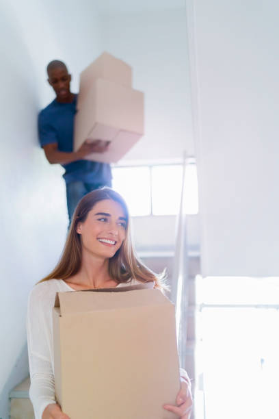 istock Smiling woman with man carrying boxes on stairway 640834736