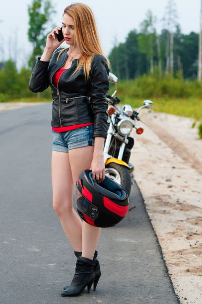istock biker young woman talking on a mobile phone while holding a motorcycle helmet 640836470