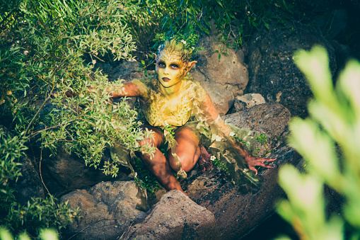 Pretty Water Nymph Fantasy Creature Near a Creek. Young woman wearing stage makeup and acting outdoors.