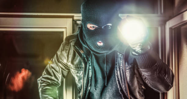 maskierter einbrecher mit pistole bricht ein und betritt die wohnung eines opfers - burglar stock-fotos und bilder
