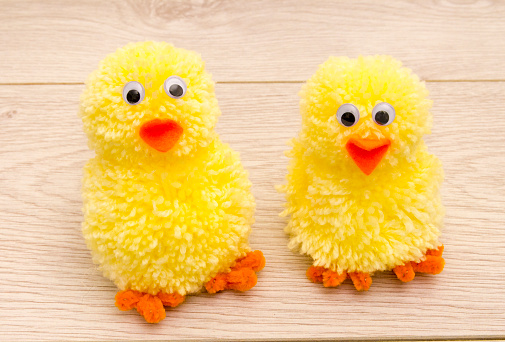 Making Easter Pom Pom Chicks using a pom pom maker and wool. You need yellow wool, two different sized pom pom makers, orange pipe cleaners for the feet, and orange felt for the beak plus stick on eyes.