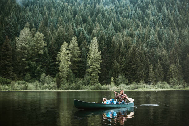 Father and Son Fishing Trip A dad and his boys enjoy some time at the lake, fly fishing for trout from the shore and a canoe. A depiction of a involved and supportive father. Shot at Trillium Lake in Oregon state. rowing boat fishing stock pictures, royalty-free photos & images