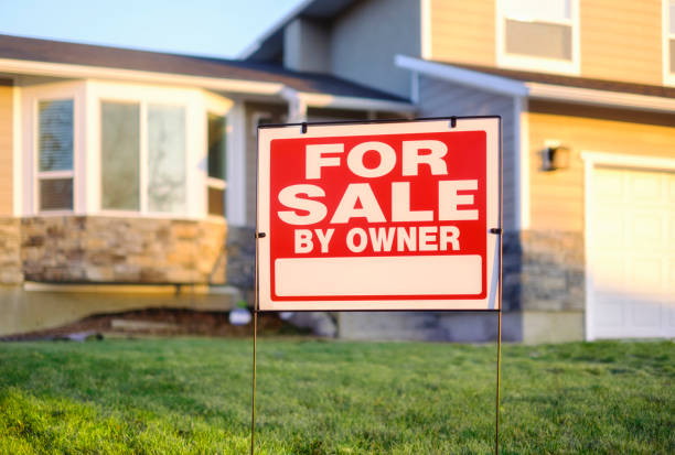 For Sale By Owner Sign and House A close up of a For Sale By Owner sign, with a two-story house in the out of focus background. house for sale by owner stock pictures, royalty-free photos & images