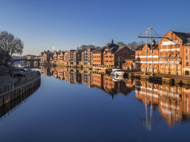 Attractive riverside of York on river Ouse on beautiful calm morning with boats, bridge and reflections stock photo