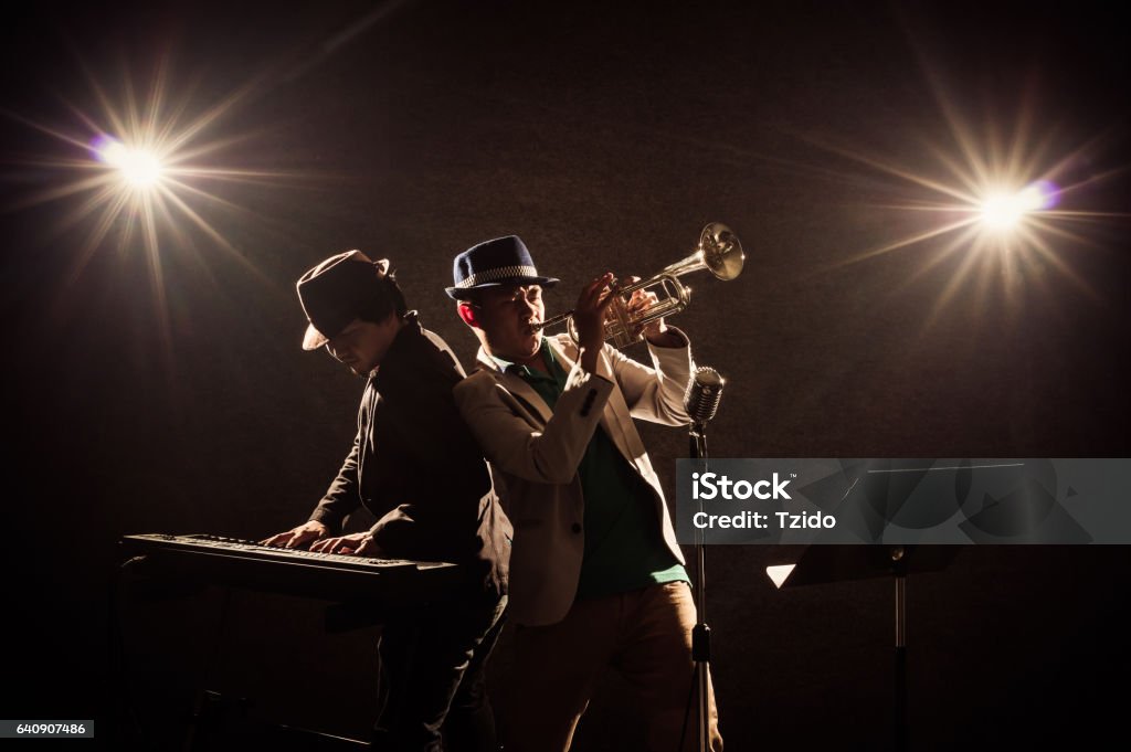 musical concept, Musicians playing a Trumpet and keyboard Musician Duo band playing a Trumpet and keyboard on black background with spot light and lens flare, musical concept Jazz Music Stock Photo