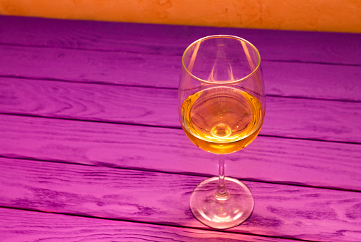White wine in the wineglass on the purple wood background