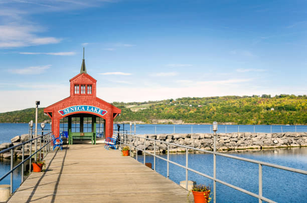 Deserted Pier on a Lake on a Sunny Fall Day Deserted Pier with a Benches and a Red Shelter at the End. Woody Hills are Visible in Background Seneca, Lake, NY watkins glen stock pictures, royalty-free photos & images