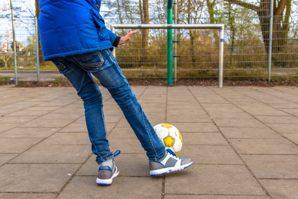 istock Boy kicking ball on urban paved soccer field 640930210