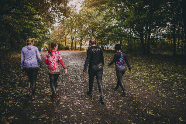 Here Come The Girls Four women are walking away from the finish line of an obstacle course. They are wearing sports clothing and are covered in mud and water. walking for a cause stock pictures, royalty-free photos & images