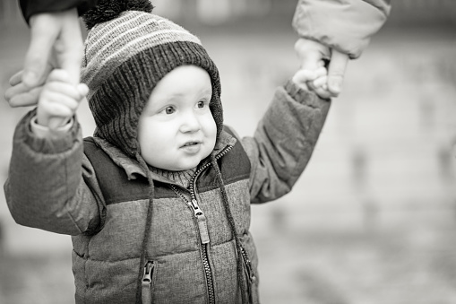 Happy family outdoor. Focus on baby boy, holding mom and daddy hands , winter time